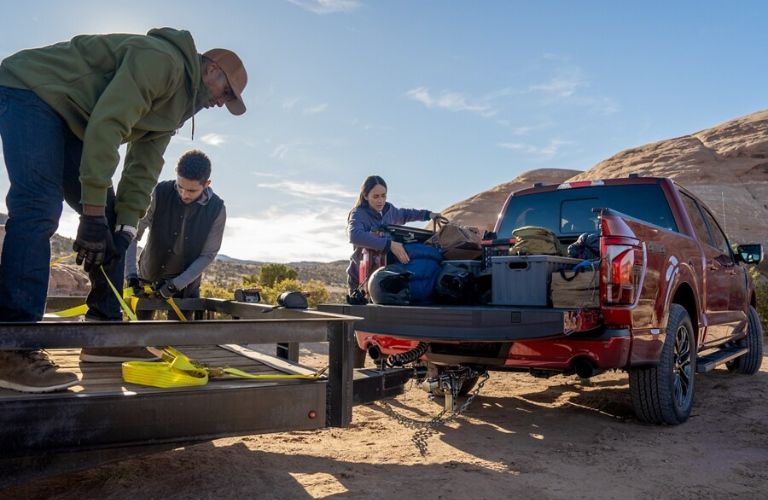 two men and a woman loading luggage on the bed of the 2024 Ford F-150® 