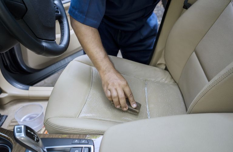 a man cleaning the seat of a car