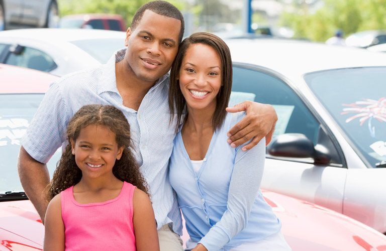 a family posing at a dealership