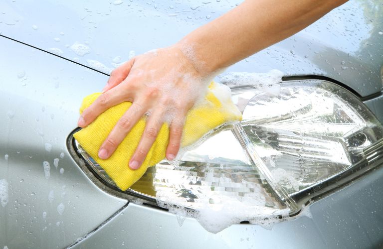 a hand cleaning the headlight of a car