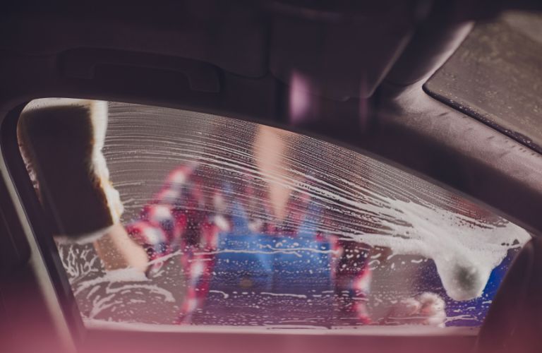 a girl cleaning the window of a car