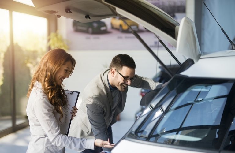 a man and woman checking a car