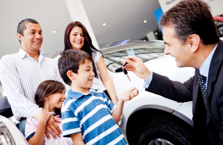 a salesman handing car keys to a kid