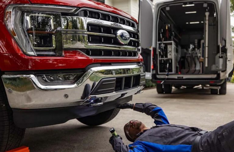 a technician looking under a Ford