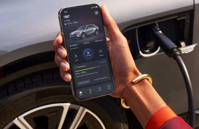 close up image of a hand holding a phone with charging status in the myCadillac app