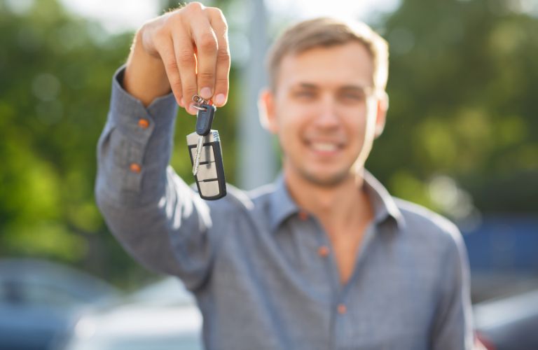 a smiling man holding a car key